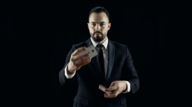 Profesyonel sihirbaz içinde bir siyah takım elbise gerçekleştirir kart numaraları, yapım Fan kartları dışarı. El çabukluğu. Arka plan siyahtır.