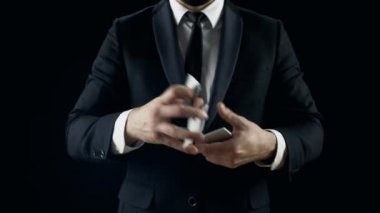 Siyah bir takım elbise içinde profesyonel sihirbaz el çabukluğu kart numaraları gerçekleştirir. Arka plan siyahtır.