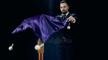 Profesyonel sihirbaz tablo yanılsama uçan gerçekleştirir. Muhteşem görünüyor. Siyah bir arka plan üzerinde ateş.