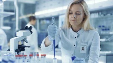 Kadın araştırma bilim adamı Micropipette dolum Test tüpleri kullanır. Bilim adamı iş büyük bir laboratuvar / Araştırma Merkezi.