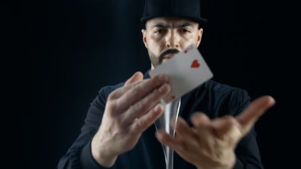 Professional Street Magician in a Cap Performs Card Disappearance and Appearance Sleight of Hand Trick Multitple Times. Background is Black. — Stock Video