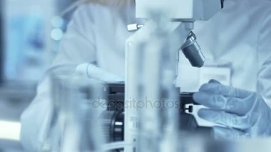 Tıbbi araştırma bilim adamı, mikroskop altında örnekleri ile Slided bakar. O bir profesyonel olduğunu.