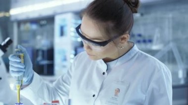 Kadın araştırma bilim adamı Micropipette dolum Test tüpleri büyük bir Modern laboratuvar olarak kullanır. Arka plan bilim adamları çalışıyoruz.