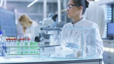 Tıbbi araştırma bilim adamı inceler laboratuvar fareler ve mikroskop altında doku örnekleri üzerinde görünüyor. O ışık bir laboratuarda çalışıyor.