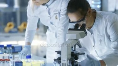 Tıbbi araştırma bilim adamı damla Her meslektaşım inceler ve slayt üzerinde bu mikroskop altında örnek. Onlar Modern bir laboratuvarda iş.