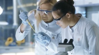 Tıbbi araştırma bilim adamı damla Her meslektaşım inceler ve slayt üzerinde bu mikroskop altında örnek. Onlar Modern bir laboratuvarda iş.