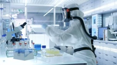 Tıbbi Viroloji araştırma bilim adamı eserlerinde bir Hazmat uygun maske ile o Test tüpleri buzdolabı kutusu ve kullanır Micropipette çıkarıyor. O bir steril yüksek teknoloji Laboratuvarı, araştırma tesisi çalışır.