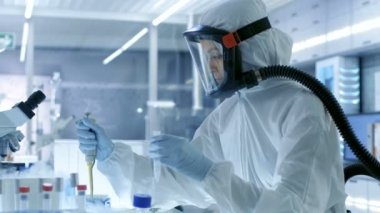 Tıbbi Viroloji araştırma bilim adamı eserlerinde bir Hazmat uygun maske ile o Test tüpleri buzdolabı kutusunda çıkarıyor. O bir steril yüksek teknoloji laboratuarında çalışıyor / araştırma tesisi.