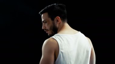 Sırtı kameraya ile Singlet ayakta giyen yaralı yüzü olan agresif adam etrafında döner ve agresif fotoğraf makinesine benziyor. Arka plan izole siyahtır,