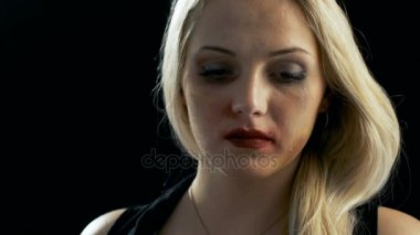 Yakın çekim Shot üzgün ağlamaya sarışın kadın ve sonra kameraya bakarak çürük. Şiddet Tema. İzole siyah arka plan üzerine ateş.