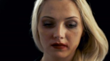 Yakın çekim Shot üzgün ağlamaya sarışın kadın ve sonra kameraya bakarak çürük. Şiddet Tema. Arka plan izole siyahtır.