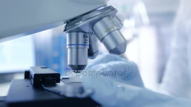Os cientistas de pesquisa médica colocam slides no lugar e olhando para amostras sob microscópio. Ela trabalha em um laboratório moderno brilhante . — Vídeo de Stock