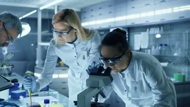 Team av medicinsk forskning forskare gemensamt arbetar på en ny Generation experimentella läkemedelsbehandling. Laboratoriet ser upptagen, ljusa och moderna. — Stockvideo