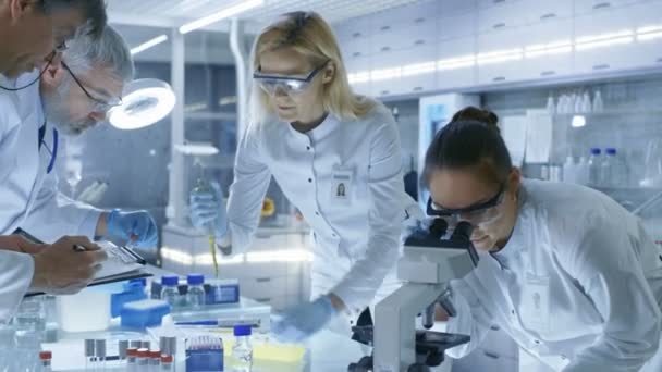 Team av medicinsk forskning forskare gemensamt arbetar på en ny Generation experimentella läkemedelsbehandling. Laboratoriet ser upptagen, ljusa och moderna. — Stockvideo