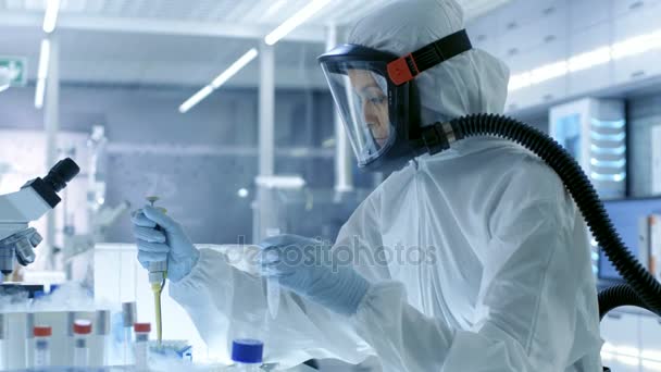 Medical Virology Research Scientist Trabalha em um terno Hazmat com máscara, Ela tira tubos de teste da caixa de geladeira. Ela trabalha em um laboratório estéril de alta tecnologia / instalações de pesquisa . — Vídeo de Stock