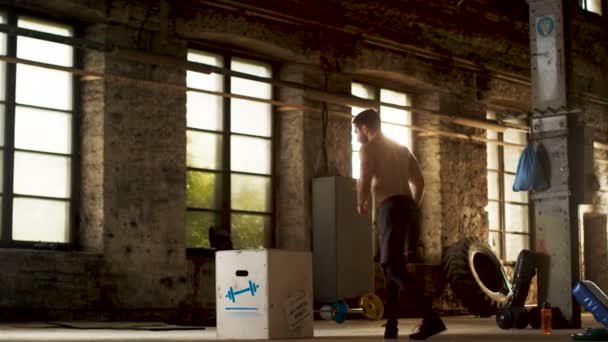 Athletic Shirtless Fit Man Energeticamente Box Jumps in Hardcore Gym doing Part of Cross Fitness Training Program. Man is Sweaty from Intense Workout / Exercício, Ginásio está no local da fábrica industrial . — Vídeo de Stock