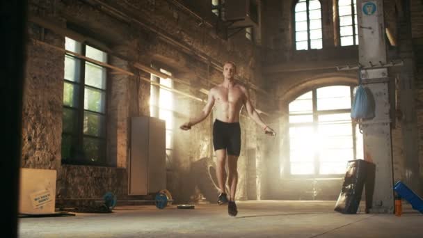 Gespierde Fit Man oefeningen met Jump / springtouw in een verlaten fabriek Hardcore Gym. Hij is bezwete uit zijn kruis Fitness Training vermoeiend. — Stockvideo