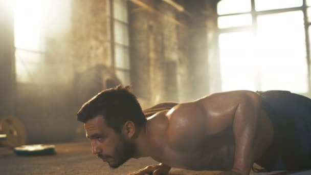 Muscular hombre sin camisa cubierto de sudor hace flexiones en una fábrica abandonada remodelado en el gimnasio. Parte de su entrenamiento Cross Fitness / entrenamiento de intervalo de alta intensidad . — Vídeos de Stock