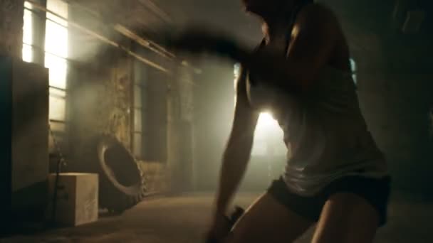 강한 운동 여 자가 연습 그녀의 한 부분으로 전투 로프 피트 니스 체육관 운동 루틴을 교차. 그녀는 땀과 체육관으로 개조 하는 버려진된 공장에서 이루어지는 훈련으로 덮여. — 비디오