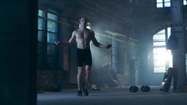 Athletic Shirtless Fit Man Esercizi con salto / saltare corda in una fabbrica deserta Hardcore Gym. E 'ricoperto di sudore dal suo intenso allenamento Cross Fitness. . — Video Stock