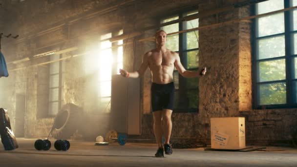 Athletic Shirtless Fit Man Exercícios com pular / pular corda em uma fábrica deserta Hardcore Gym. Ele está coberto de suor de seu treinamento intensivo de aptidão cruzada . — Vídeo de Stock