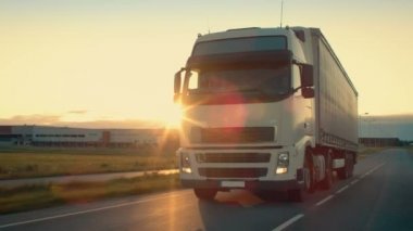 Açık görüş kamerası yarı kamyon kargo Trailer karayolu üzerinde sürüş ile izler. O içinde belgili tanımlık geçmiş gün batımı ile endüstriyel depo bölgesi ile hız.