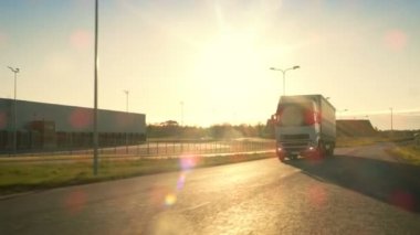 Açık görüş kamerası yarı kamyon kargo Trailer karayolu üzerinde sürüş ile izler. O içinde belgili tanımlık geçmiş gün batımı ile endüstriyel depo bölgesi ile hız.