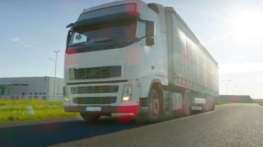 Büyük beyaz yarı kamyon kargo römork ile arka planda güzel bir gün ile sanayi bölgesi boş yolda hamle.