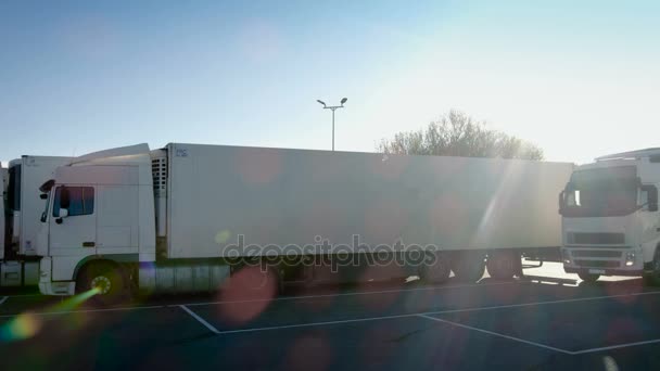 Caminhão branco com semi-reboque de carga dirige para o lugar de estacionamento e estaciona com outros veículos . — Vídeo de Stock