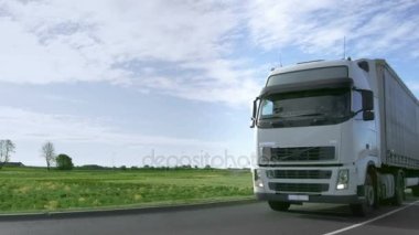 Alanları ve arka planda endüstriyel depolar otobanda hız beyaz yarı kamyon kargo römork ile Frontal View sürücüler.