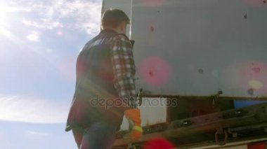 Kamyon şoförü kamyon kargo karavanına kapılarını kapatır. Profesyonel sürücü ağır eldiven giyer. 