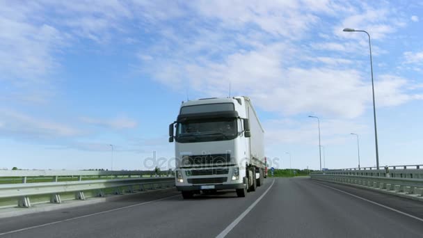 Vitesse semi-camion blanc avec remorque de fret conduit sur la route. Le camion est le premier dans la colonne des véhicules lourds, le soleil brille . — Video