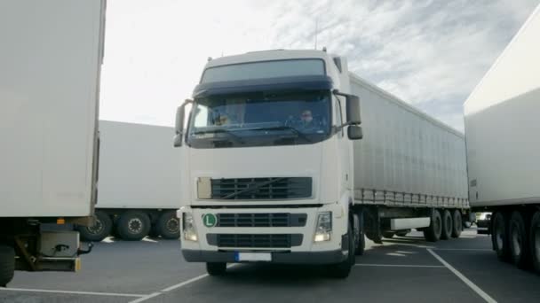 Vista frontal do caminhão semi branco com reboque de carga dirige para o lugar de estacionamento e estaciona com outros veículos . — Vídeo de Stock