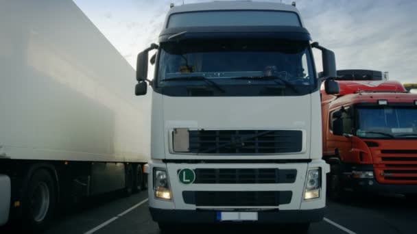 Πρόσθια όψη του λευκού ημι φορτηγό με ρυμουλκούμενο φορτίου οδηγεί σε θέση στάθμευσης και πάρκα με άλλα οχήματα. — Αρχείο Βίντεο