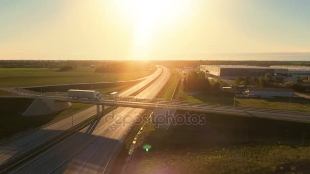 Vista aérea del camión semirremolque blanco con remolque de carga que pasa el paso elevado / puente de la carretera. Dieciocho Wheeler es nuevo, los almacenes de carga se ven en el fondo . — Vídeo de stock