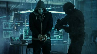 Maskeli Hacker kelepçe takan tamamen silahlı Specia tarafından korunuyor