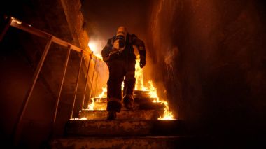 Strong and brave Firefighter Going Up The Stairs in Burning Buil clipart