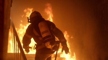 Brave Firefighter Runs Up The Stairs. Raging Fire is Seen Everyw clipart