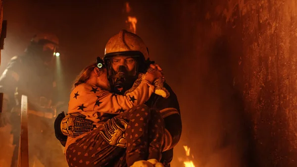 Valiente bombero desciende escaleras de un edificio en llamas y sostiene Sa — Foto de Stock