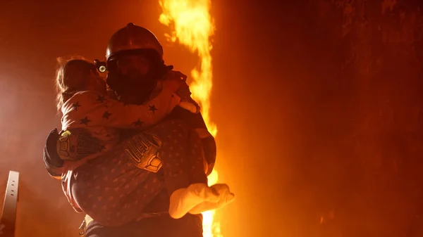 Valiente bombero sostiene a chica salvada en sus brazos en un edificio en llamas — Foto de Stock