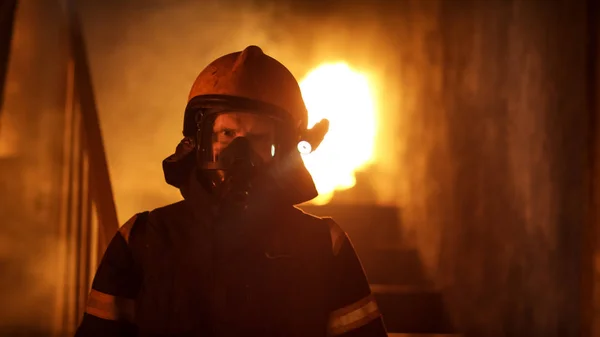 Portraitaufnahme eines tapferen Feuerwehrmannes, der in einem brennenden Gebäude steht — Stockfoto