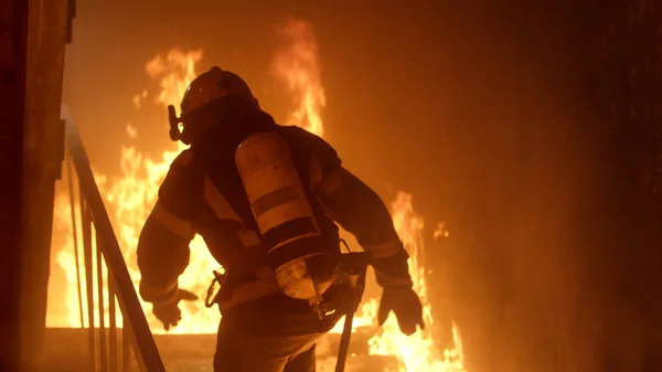 O corajoso bombeiro corre pelas escadas. Fogo furioso é visto em todos os lugares — Fotografia de Stock