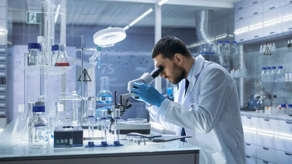 Research Scientist Looks into Microscope. He's Conducts Experime — Stock Photo, Image