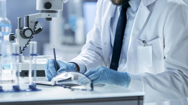 Научный сотрудник записывает наблюдения за экспериментами. He 's Wor
