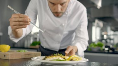 Ünlü şef onun özel balık yemek bazı yeşillikleri ile süsle. O