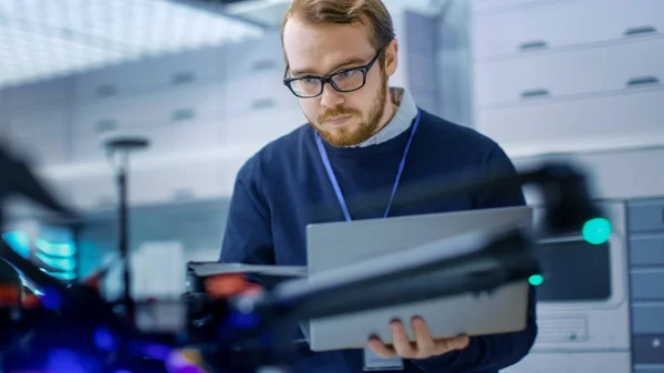 Junger Ingenieur programmiert Drohne, während er Laptop in der Hand hält — Stockfoto