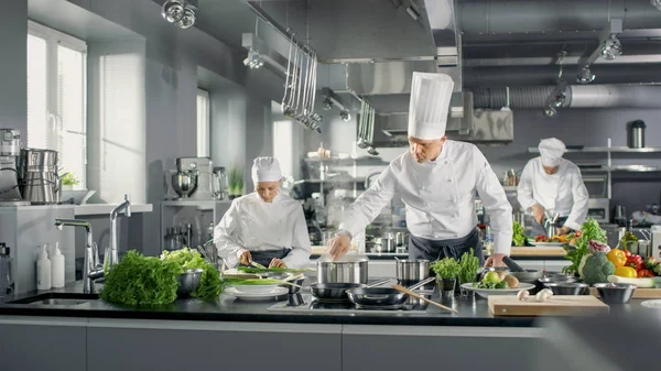 O famoso chef trabalha em uma cozinha grande do restaurante com sua ajuda. Kit — Fotografia de Stock