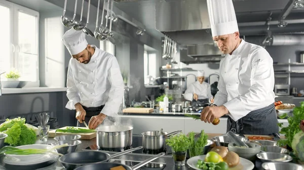 Deux chefs célèbres travaillent en équipe dans une grande cuisine de restaurant. Légumes — Photo