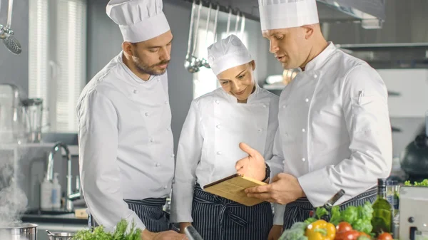 En el equipo de cocina moderna de los cocineros utilizan Tablet Computer para Reci —  Fotos de Stock