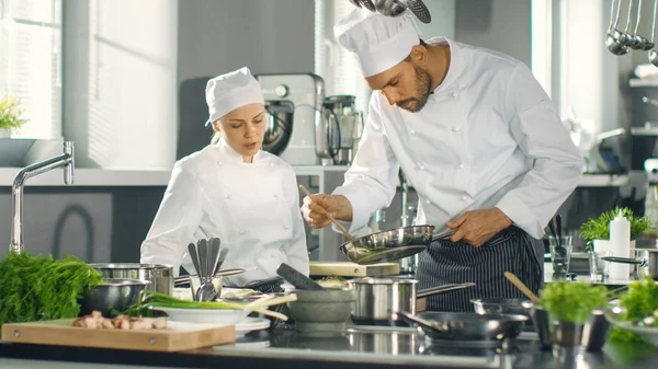 O chef famoso e seu aprendiz fêmea preparam prato especial em um — Fotografia de Stock